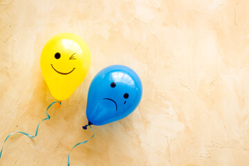 Emotions concept. Happiness and depression faces on balloons, top view