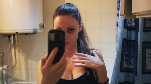 Pretty girl making a duck face, and taking a self portrait with smartphone in bathroom