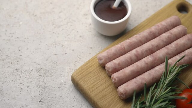 Grilled sausages on a wooden board with tomatoes, rosemary and tomato sauce, frame moves to the side, close-up