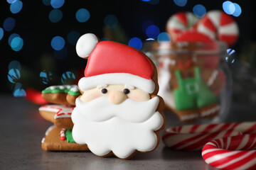 Decorated Christmas cookies on grey table against blurred festive lights