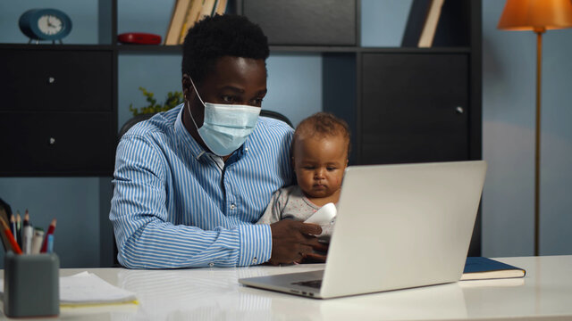 Father in mask measuring temperature to cute sick baby consulting doctor online
