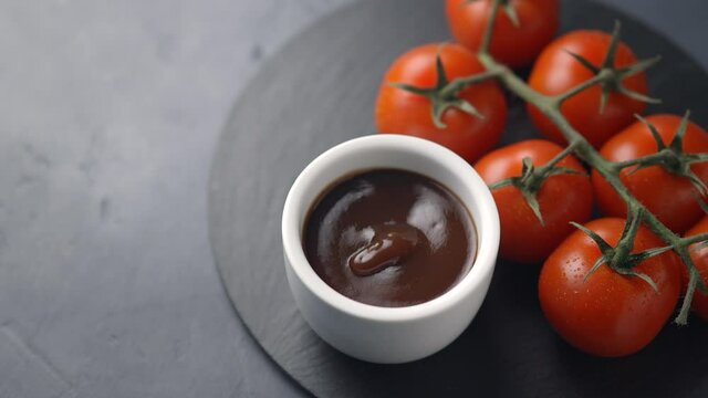 Girl takes tomato sauce with a spoon, dark background, cherry tomatoes, close-up