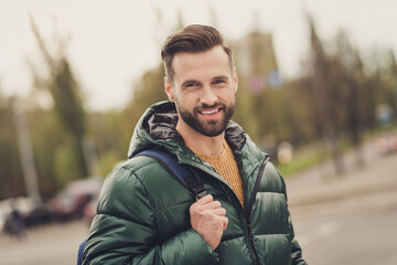 Photo of positive good mood cheerful young man wear green windbreaker schoolbag smiling walking...
