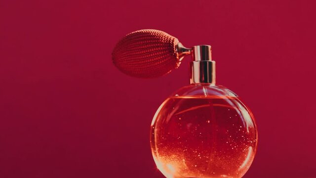 Vintage perfume bottle and shining light flares on red background, glamorous fragrance scent as luxury perfumery product for cosmetic and beauty brand, stock footage