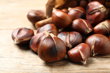 Delicious roasted edible chestnuts on wooden table, closeup