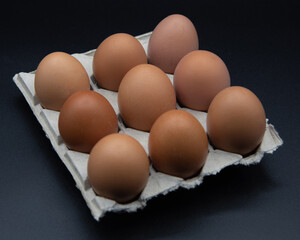 Huevos en huevera de cartón sobre fondo negro