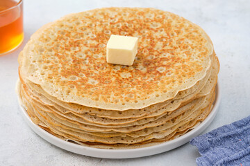 Crepes, thin pancakes with honey and butter on a white plate. Close up.