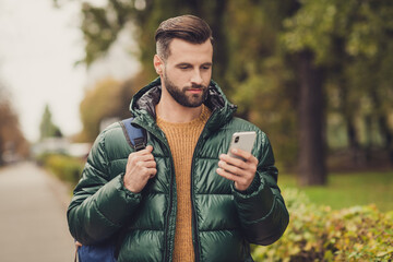 Portrait of handsome positive guy blogger look screen blog post hold rucksack free time walking...