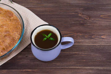 Fresh baked pie on a dark wooden surface with a cup of tea.