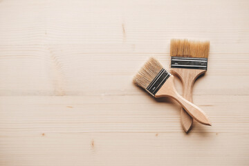 Two paint brushes with a wooden handle and natural bristles on a wooden background. Repair concept....