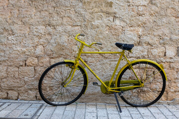 Altes gelbes Fahrrad vor einer Mauer