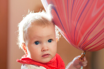 Cute blond baby with blue eyes keeping big pink baloon