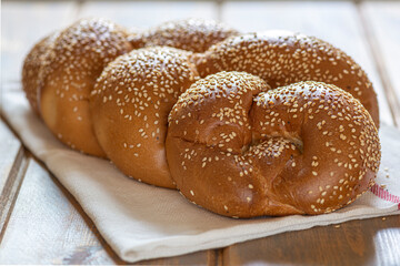 Traditional Jewish sweet Challah bread for Shabbat on a white textile on a wooden table, close up.