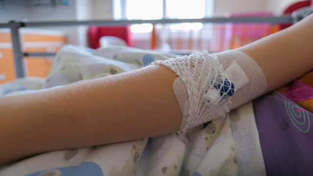 Peripheral Venous Catheter on Young Girl Patient Arm in Hospital Bed