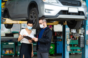 Mechanic man and woman customer wearing medical face mask protection coronavirus and check the car condition before delivery.