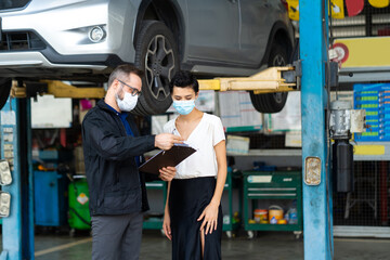 Mechanic man and woman customer wearing medical face mask protection coronavirus and check the car condition before delivery.