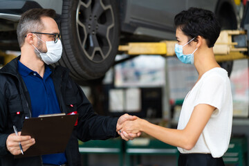 Mechanic man and woman customer wearing medical face mask protection coronavirus and check the car condition before delivery.