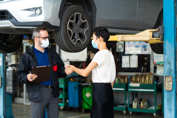 Mechanic man and woman customer wearing medical face mask protection coronavirus and check the car condition before delivery.