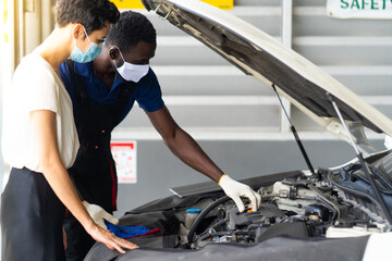 Mechanic man and woman customer wearing medical face mask protection coronavirus and check the car condition before delivery.