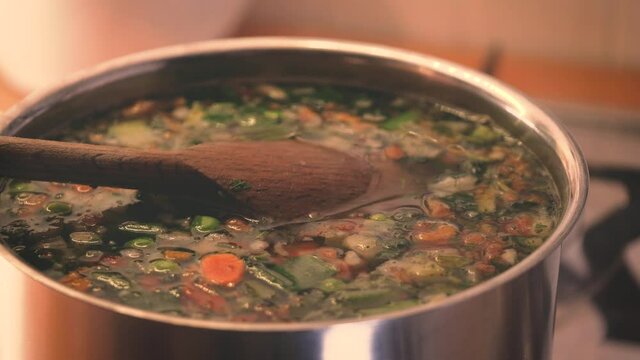 Minestrone soup boiling in the pot. Vegetarian healthy meal for dinner. Ready vegetable meal for lunch, hot and cozy soup for dinner at home. Vegetable soup with carrots, potatoes,  beans