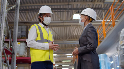 Successful partners in safety mask handshaking in warehouse of large factory