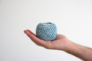 Caucasian male hand holding a ball on colorful household rope isolated on white