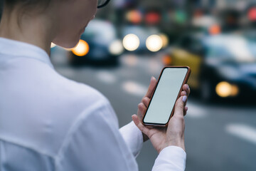 Crop anonymous woman checking smartphone while standing on roadside