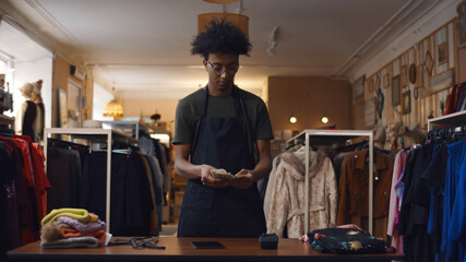 Young african male cashier counting chash on modern second-hand store