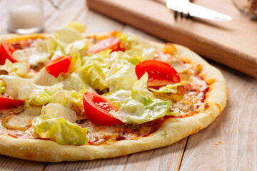 Chicken caesar pizza with tomatoes and lettuce