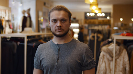 Obraz premium Young handsome confident man looking at camera standing at clothing store