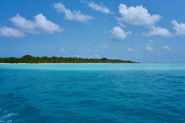 Golden beach under blue sky and clear blue water in the maldives