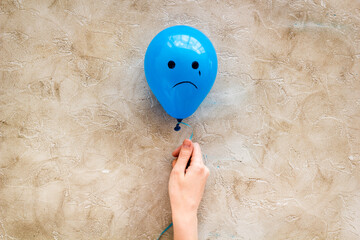 Sadness emotion face on balloon - depression mood background. Top view, copy space