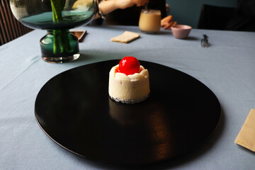 cake with chocolate plated on a black plate with a cherry on top
