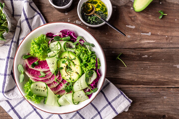 Fresh salad. Bowl with fresh raw vegetables -avocado, lettuce, microgreen, cabbage, cucumber. Healthy food. Vegetarian buddha bowl. Top view. Flat lay