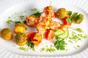 Grilled salmon kebab served with tomatoes cucumbers and baked potatoes with spices