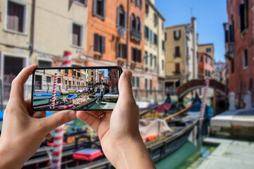 Tourist taking photo of traditional fancy decorated gondola in venetian water canal in Venice,...