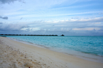 Golden beach under blue sky and clear blue water in the maldives