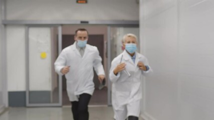 Nurse and doctors in safety mask running in hospital corridor having emergency case - Powered by Adobe