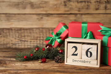 Block calendar with Boxing Day date near gifts on wooden table. Space for text