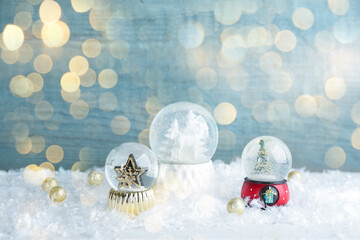 Beautiful Christmas snow globes on light blue background, bokeh effect. Space for text