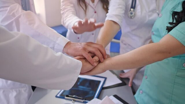 Close-Up of Medical Workers Stack Hands on the Table Together for Support at Work. Team of Doctors at Modern Hospital. Team spirit at modern at Clinic.