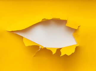 Torn hole in yellow paper with a white background. Concept for placing text or other elements, copy...