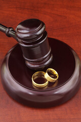 Two wedding rings and wooden judge gavel. Divorce and marriage concept.