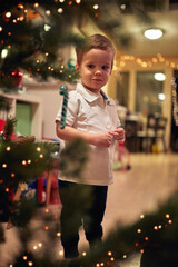 A little boy excited about a Christmas tree at home. Together, New Year, family, celebration