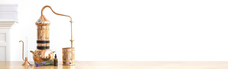 Distilling apparatus alembic with esential oil flowers at the wooden table