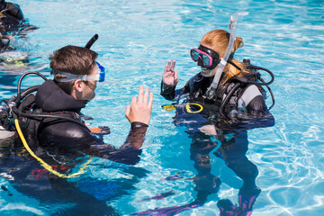 Scuba dive training in a pool students showing the ok sign above water.