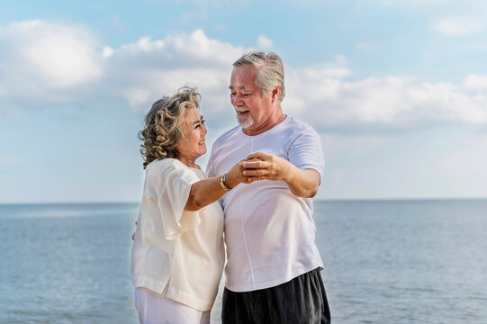 Happy asian senior retired couple, relax smiling elder man and woman enjoying with retired vacation at sea beach outdoor. Health care, Family outdoor lifestyle