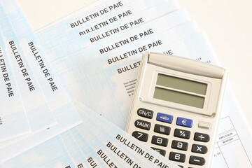 calculatrice grise et bulletin de paie