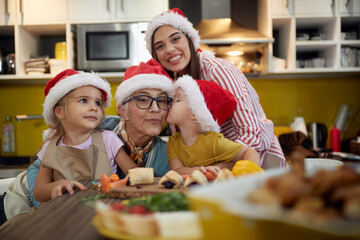Grandma and mother posing for a photo with children in the kitchen at Xmas. Christmas, family, together