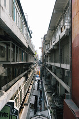 elevated street view of a narrow alley street between commerical residential industrial buildings with several stories, and people shopping below